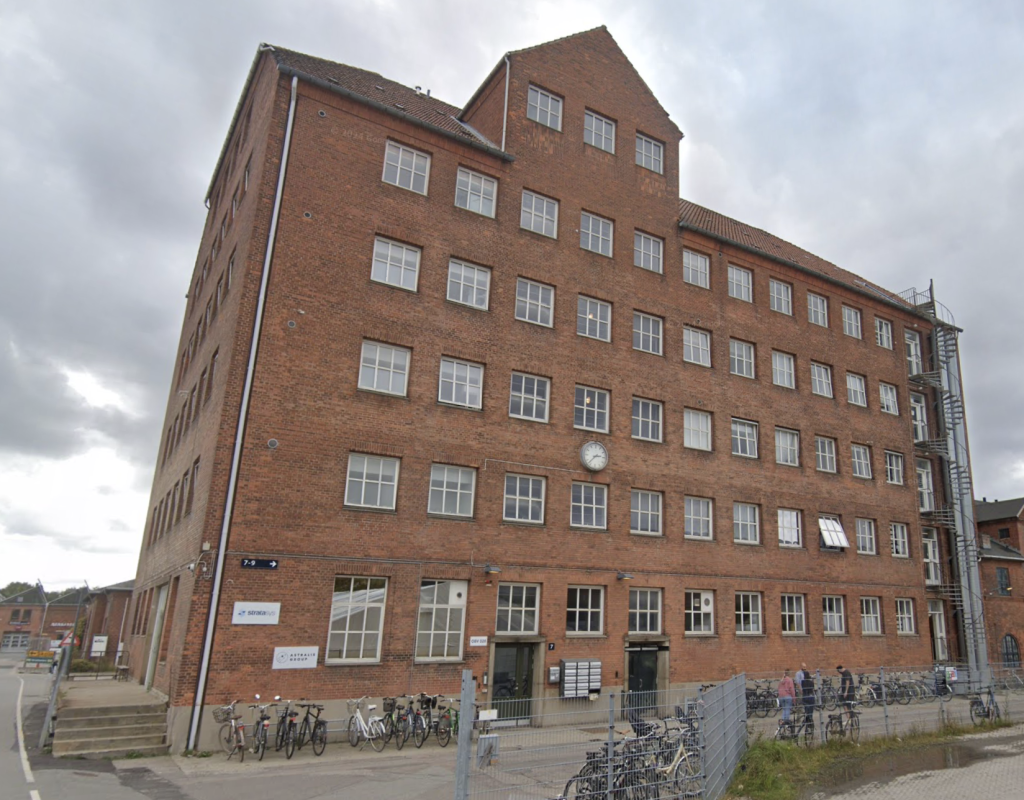 a brick building with many windows and bicycles parked in front of it